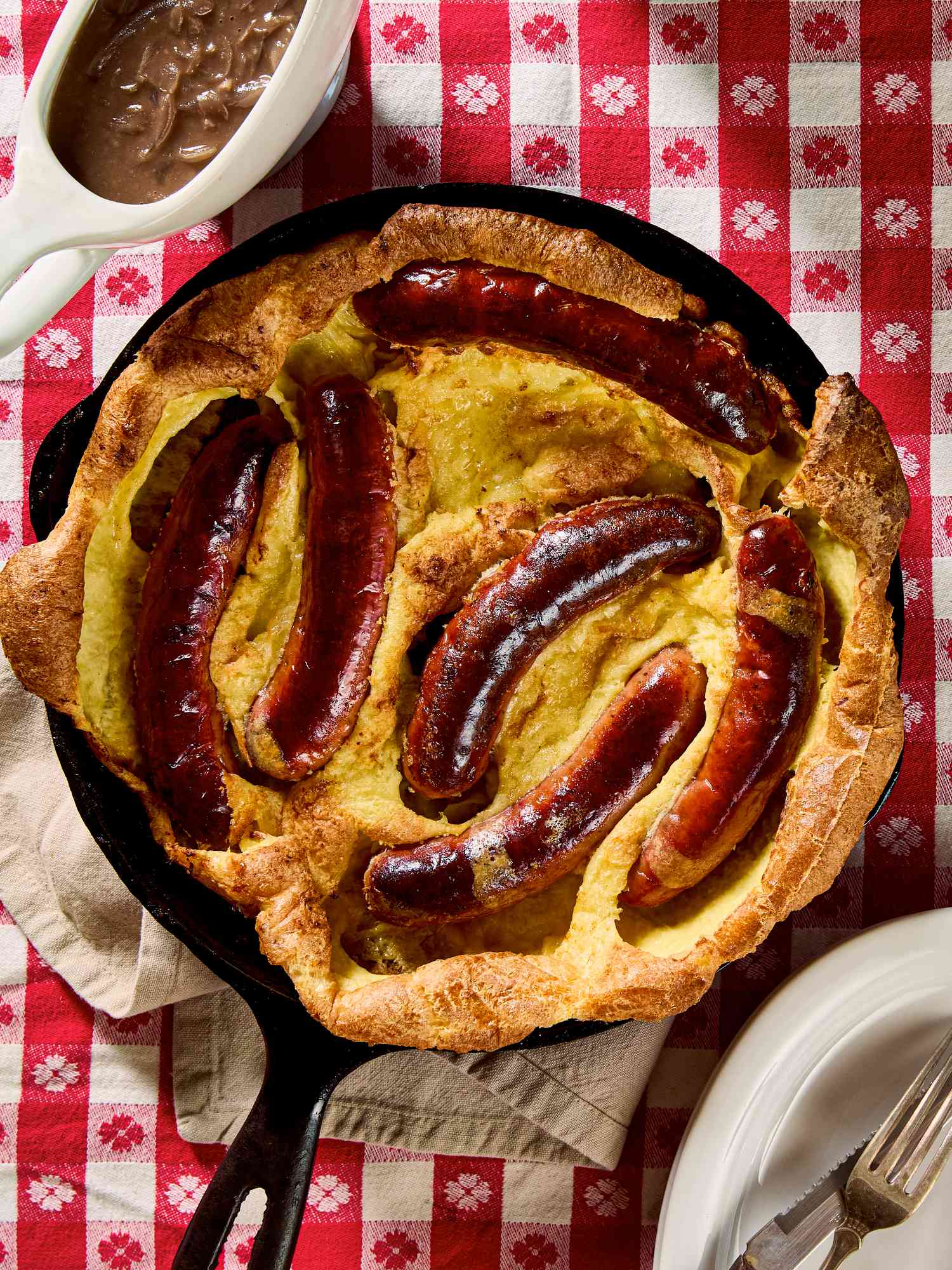A skillet with a Toad in the Hole dish on a checkered tablecloth