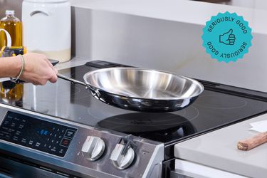 a person lifting the all-clad skillet from an electric stovetop