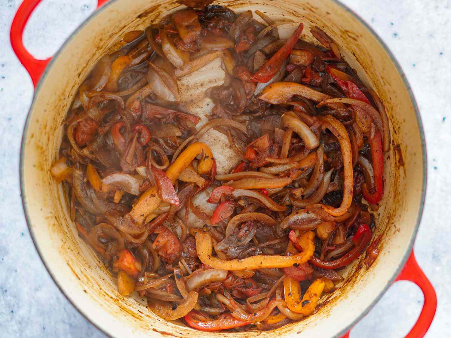 Peppers and onion being sautÃ©d in Dutch oven