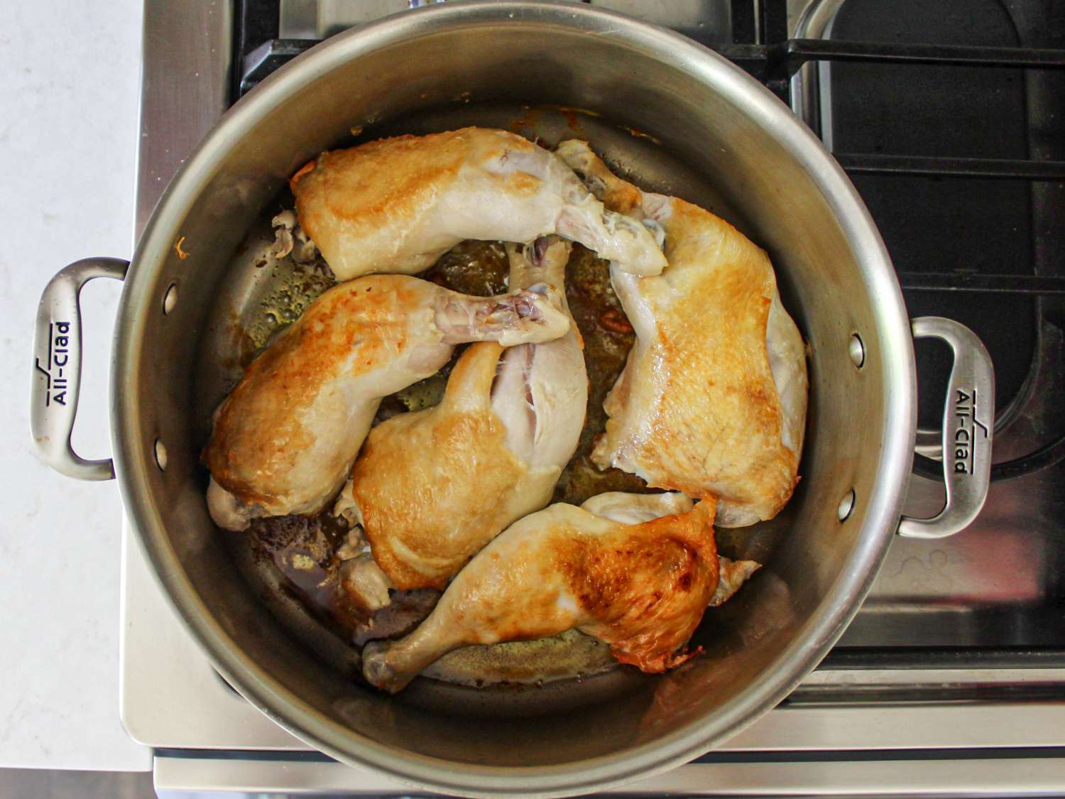 Chicken, skin side down, cooking in a pot on a stove