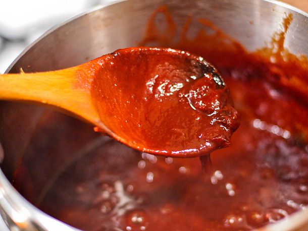The consistency of the sauce is checked with a wooden spoon