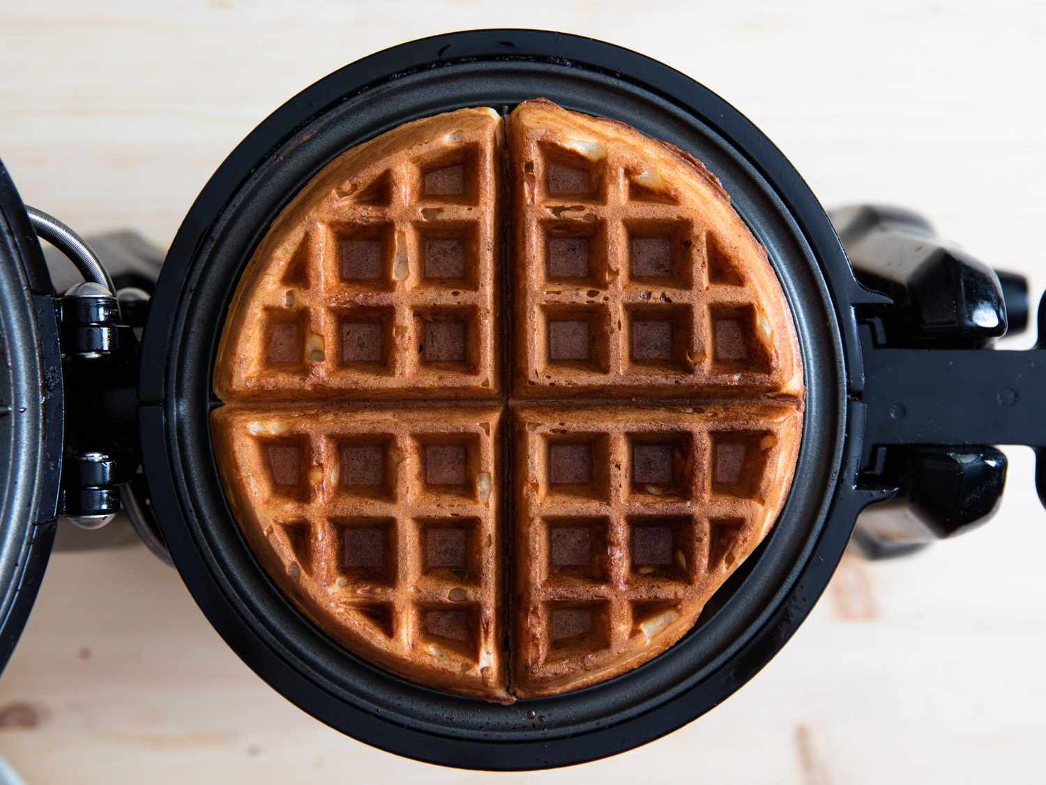 A finished yeast-raised waffle, ready to be transferred from the iron.