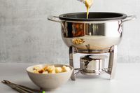 Bread being dipped into cheese fondue in the All-Clad fondue pot.