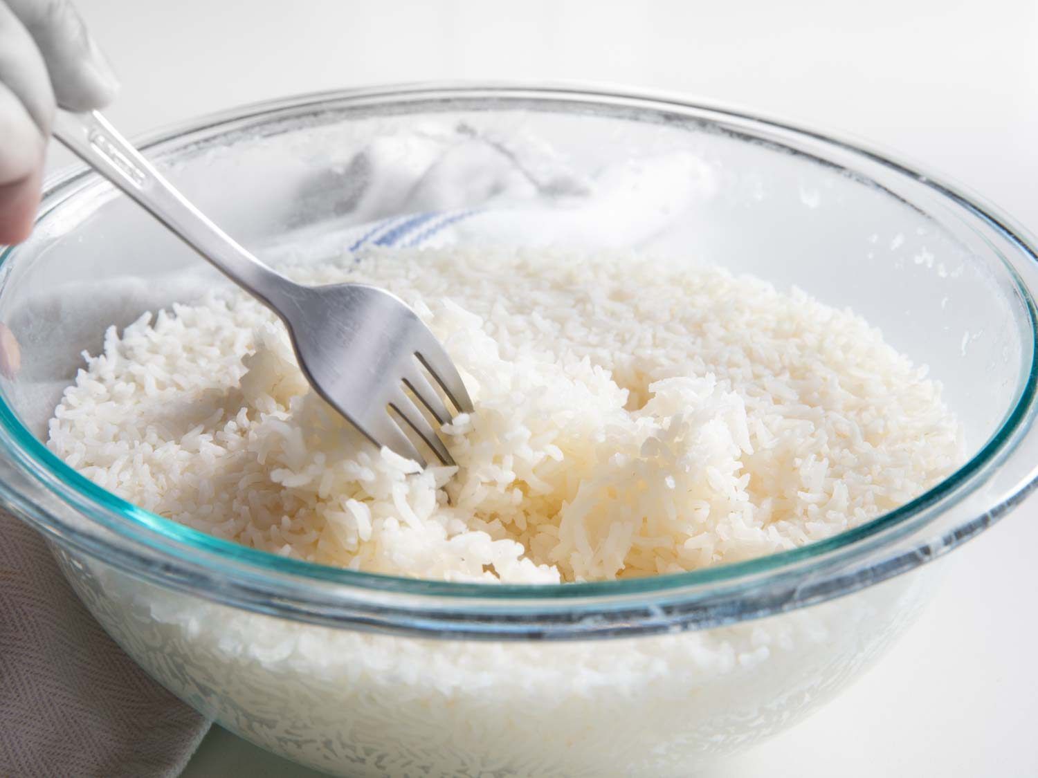 Using a fork to fluff white rice cooked in the microwave.
