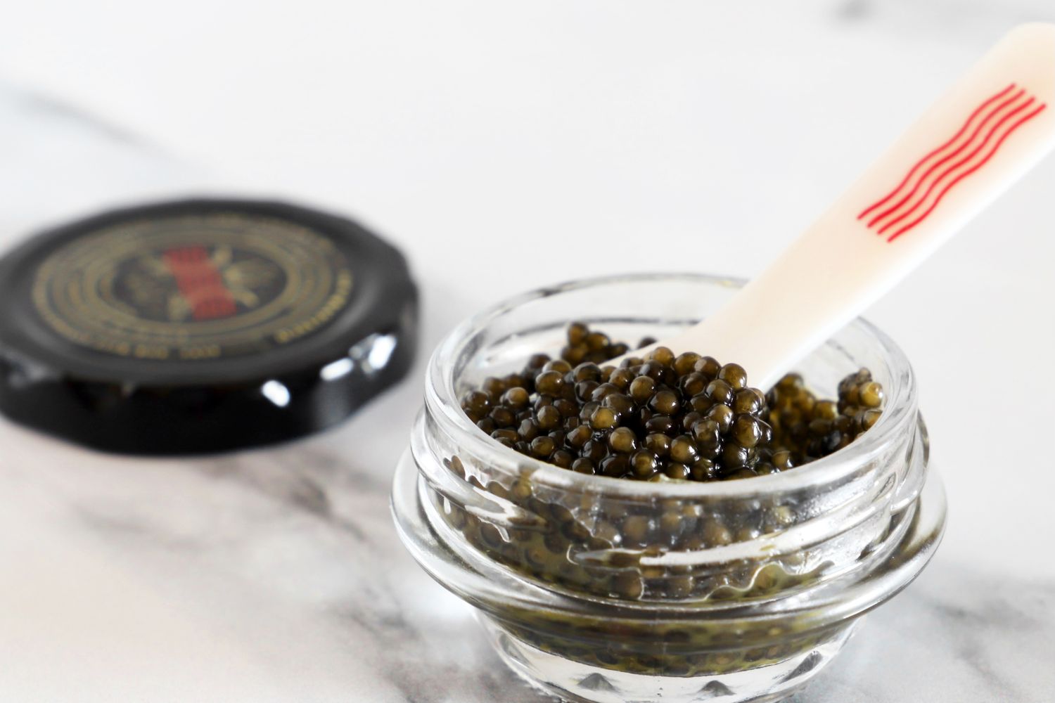 A jar of royal white sturgeon caviar from Caviar Co, opened with a mother-of-pearl spoon set inside