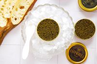 Caviar in tins served over ice with bread slices and a spoon