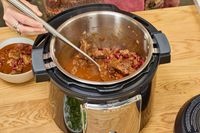A person uses a spoon to ladle stew from the Instant Pot Pro Plus Wi-Fi Smart 10-in-1 6-Quart Pressure Cooker