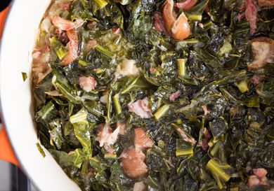 A container of braised collard greens with ham hocks. 