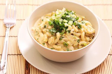 Green chile chicken mac and cheese, served in a white bowl and garnished with scallions and cilantro.