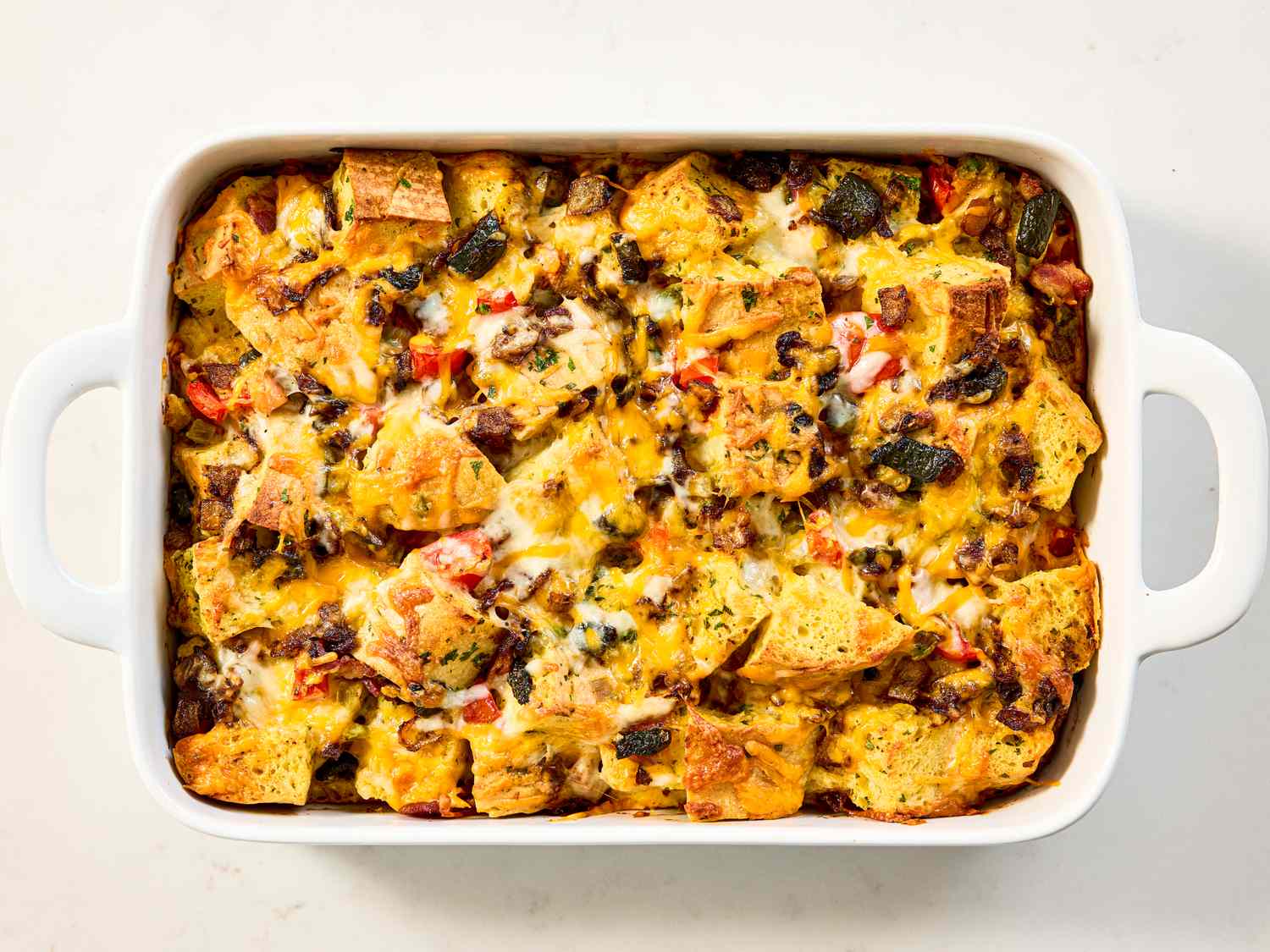 A casserole dish containing a baked strata with bread cheese and vegetables