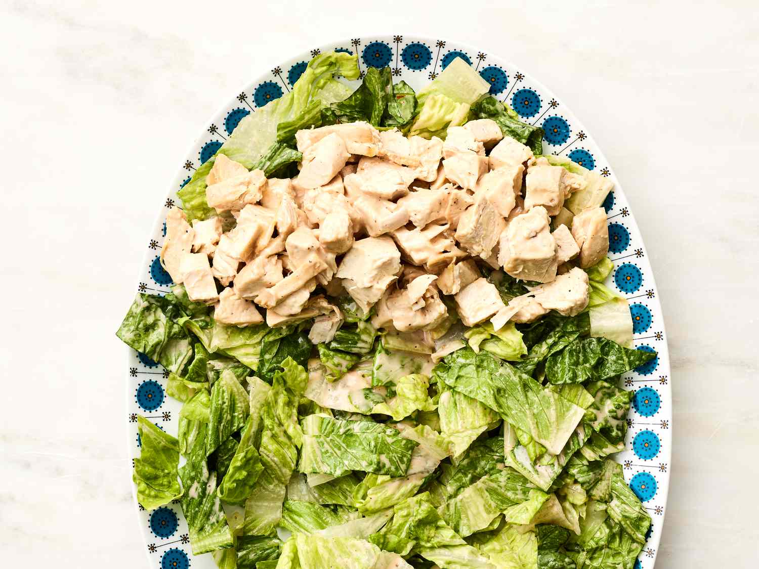 Chopped romaine lettuce with diced chicken on a platter