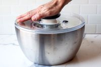 a person pressing the pump on a salad spinner