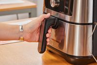 A hand grabbing the handle on the Instant Vortex Plus 6QT XL Air Fryer basket