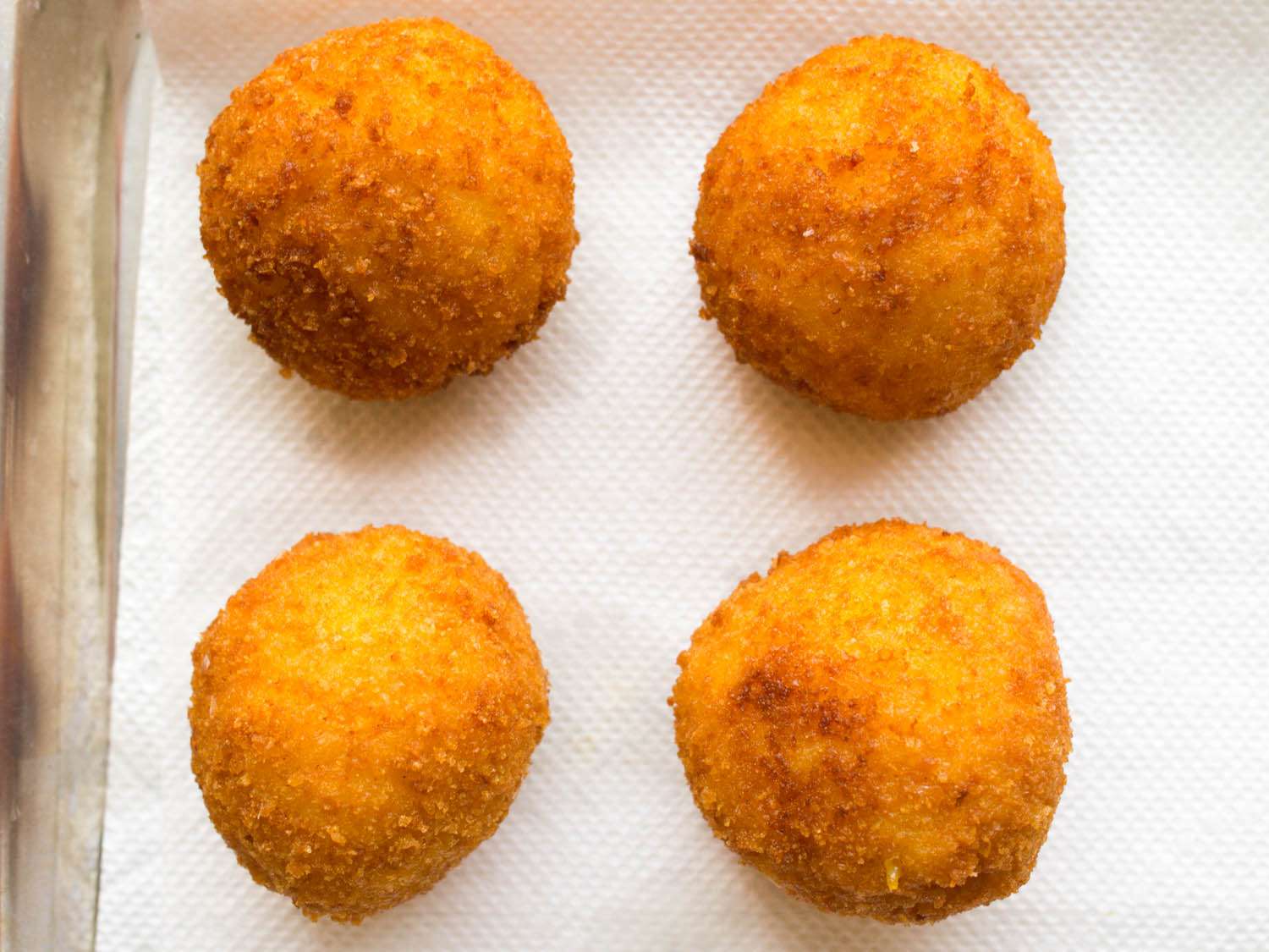 Overhead shot of arancini draining on paper towels.
