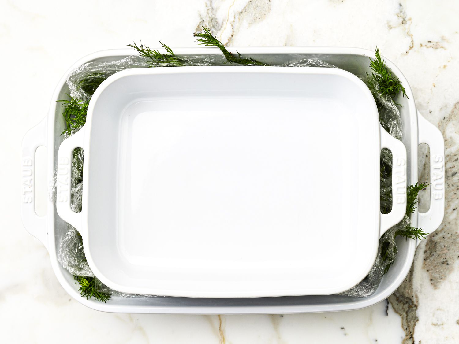 Salmon on bed of dill being weighted down with a tray