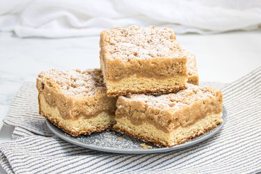 Stack of NJ Crumb buns on a plate, with a striped napkin and a white tabletop 