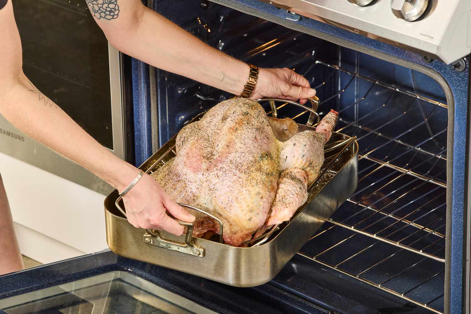 A person putting a KellyBronze Turkey into an oven