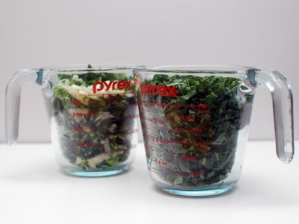 Glass measuring cups filled with chopped bok choy and kale for fried rice.