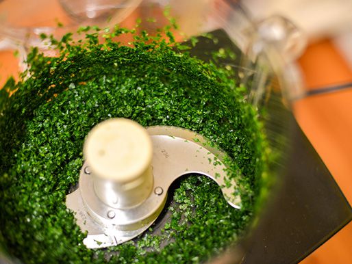 Finely chopped herbs inside a food processor.