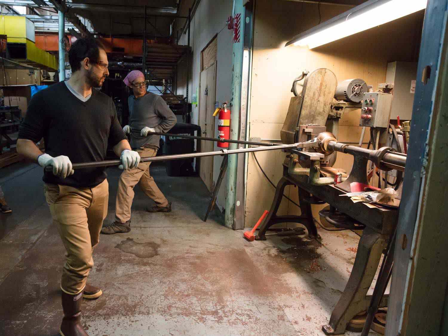 Daniel Gritzer and Jim Hamann work on a lathe to make copper saucepans.
