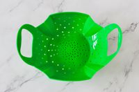 a green silicone steamer basket on a marble surface