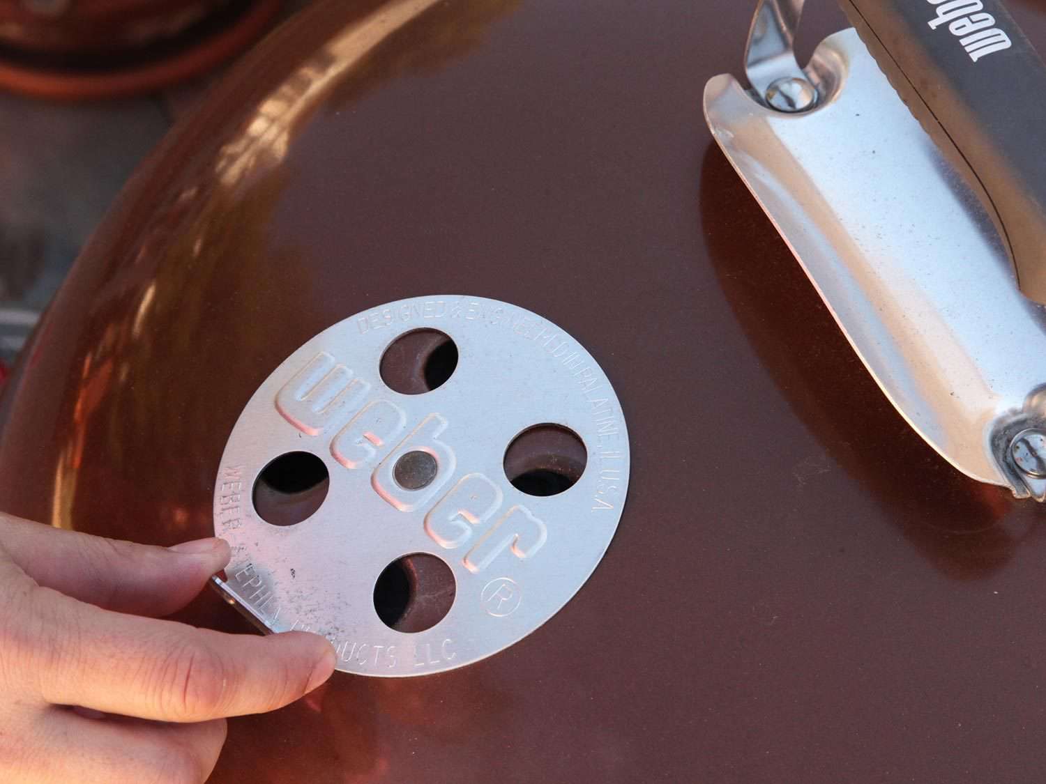 Adjusting vents on a Weber grill.