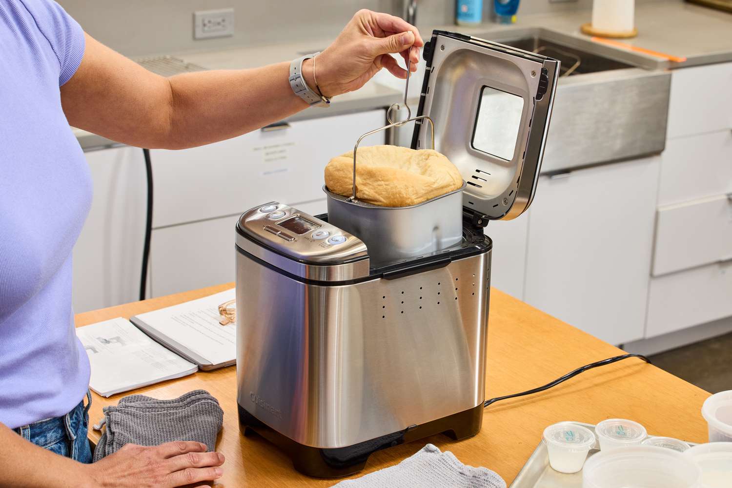 A person using a tool to remove the basket from the Cuisinart CBK-110 Compact Automatic Bread Maker