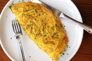 A large, diner-style omelette sprinkled with chopped chives on a plate.