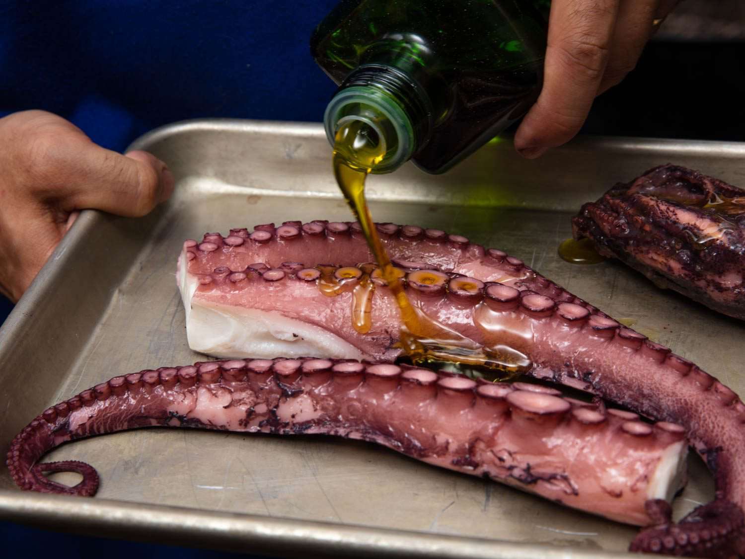 Drizzling olive oil on cooked octopus tentacles before charring them on the grill (or, alternatively, searing them in a skillet).