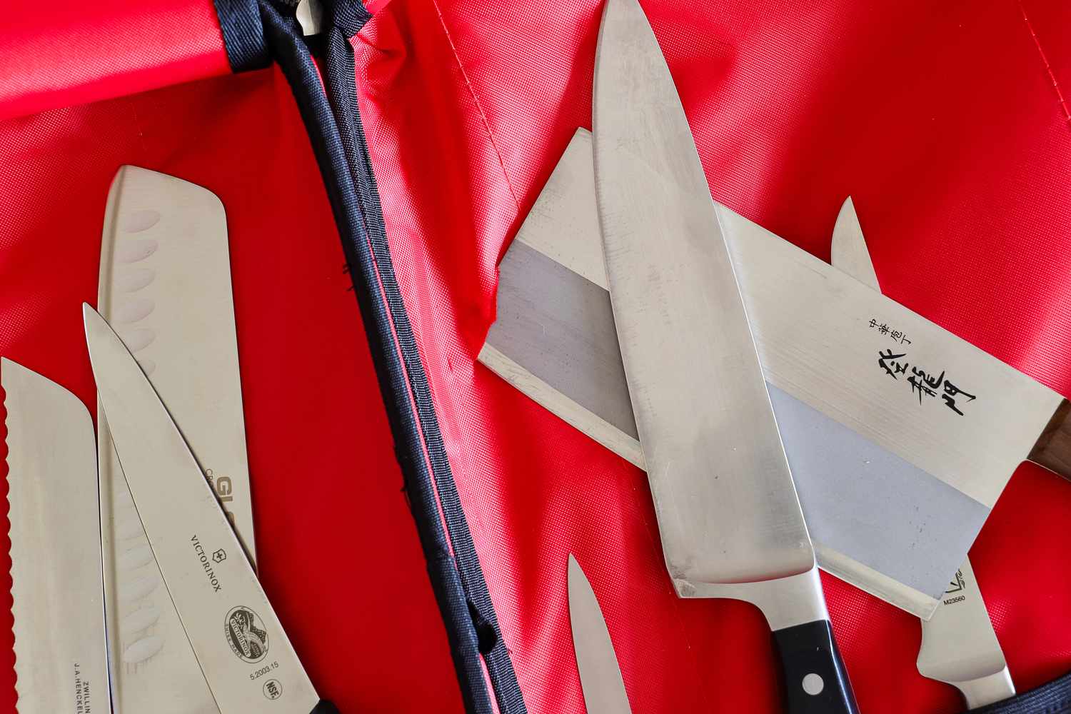 Assorted kitchen knives in a red case including a chefs knife and a cleaver