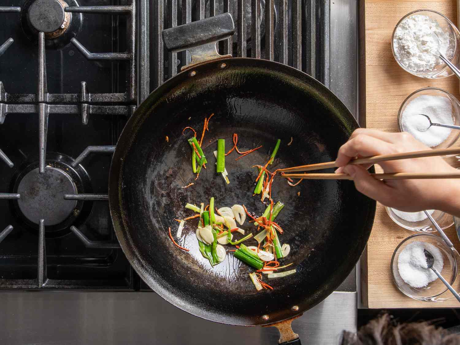 Scallions, thinly sliced dried chiles, and garlic in the wok.