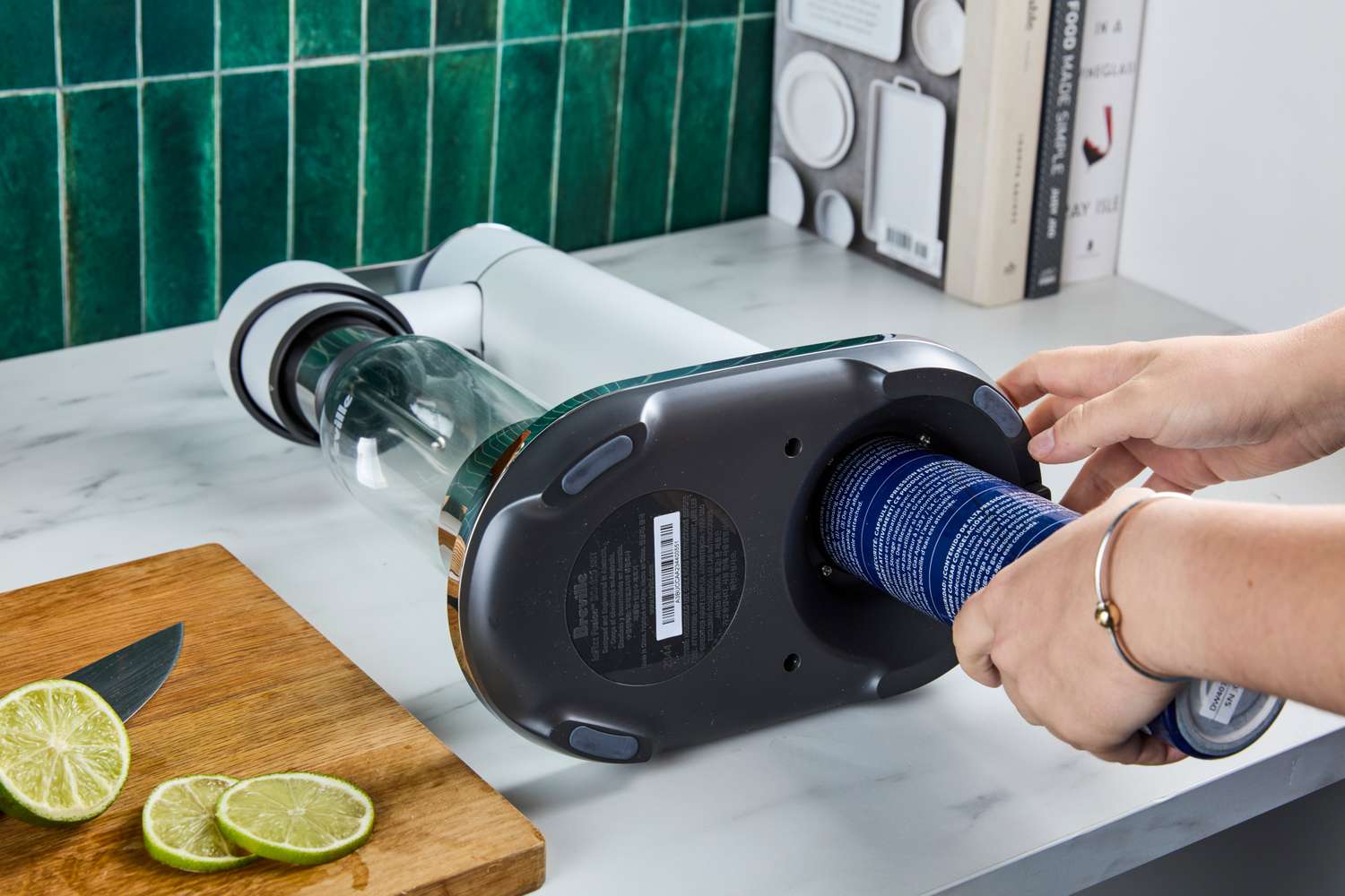 A person inserting a canister into a Breville Infuser device on a kitchen counter