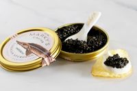 A tin of Imperial Sturgeon caviar from Marky's next to a potato chip topped with crème fraîche and caviar