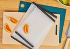 Three plastic cutting boards on a wooden countertop.