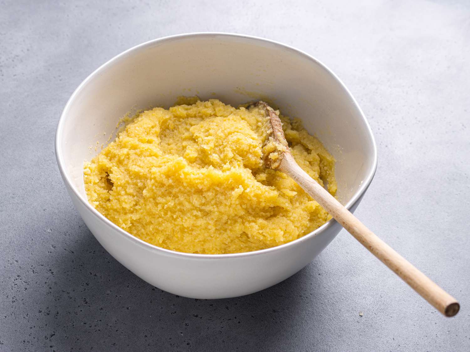 A wooden spoon resting in a bowl of mixed eba