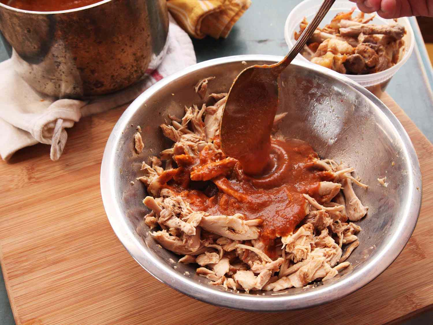 Sauce is added to a bowl of shredded chicken.