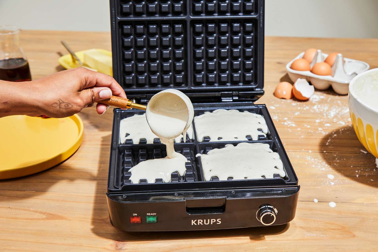 Person pouring batter into Krups 4-Slice Belgian Waffle Maker