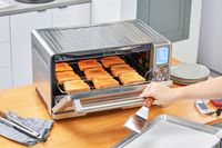 A person opening the Breville the Joule Oven Air Fryer Pro door while holding a spatula