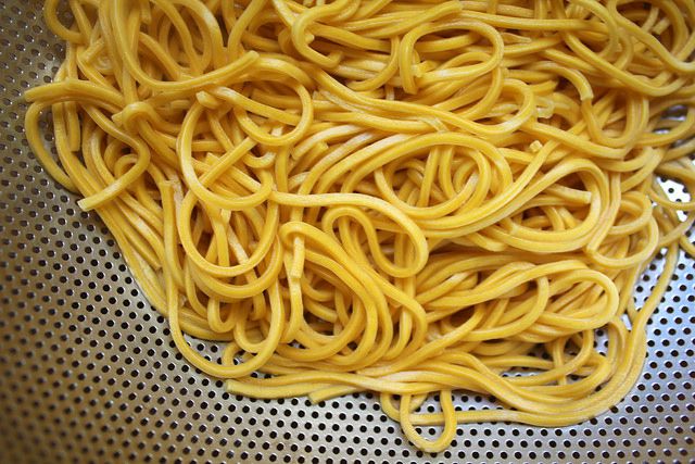 Cooked lo mein noodles are drained in a colander.