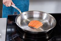 A person flips a piece of salmon in the Made In 12-Inch Stainless Steel Skillet