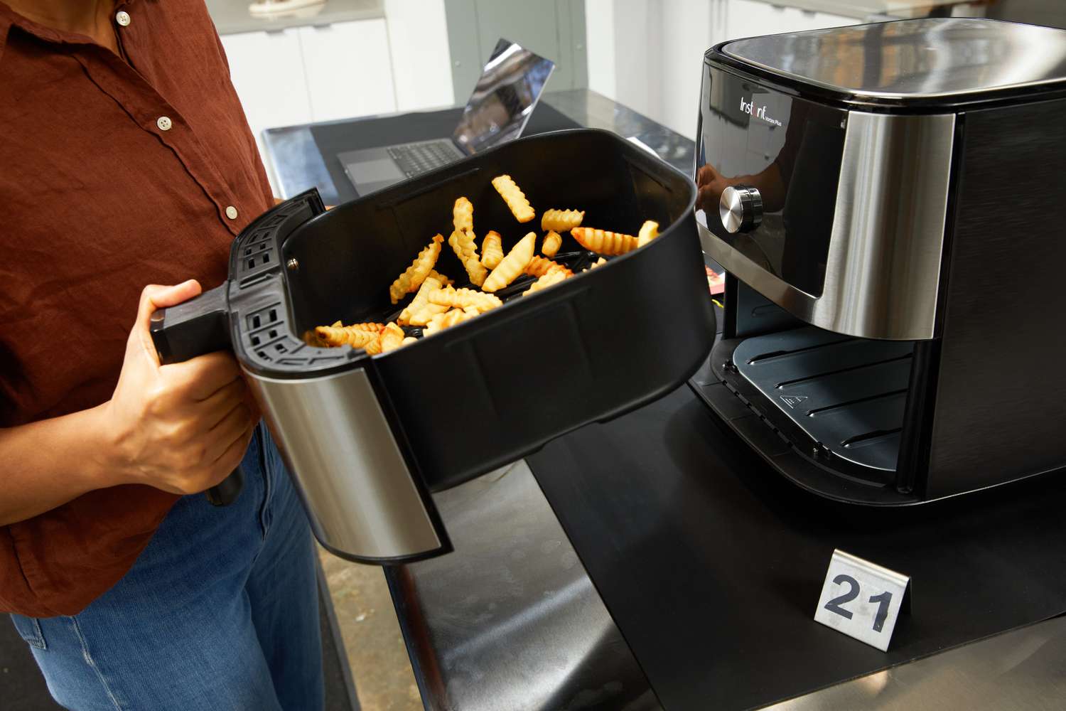 A person tossing fries in the Instant Pot Vortex Plus 6-Quart 6-in-1 Air Fryer's basket