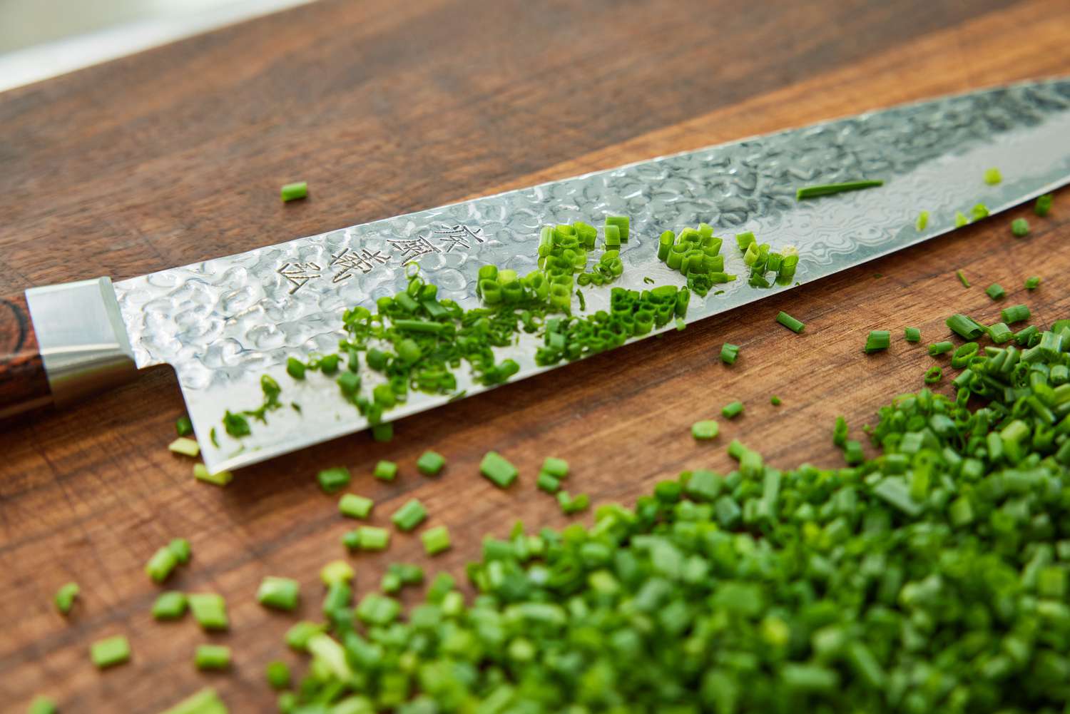 a japanese style chef's knife on a cutting board after chopping chives