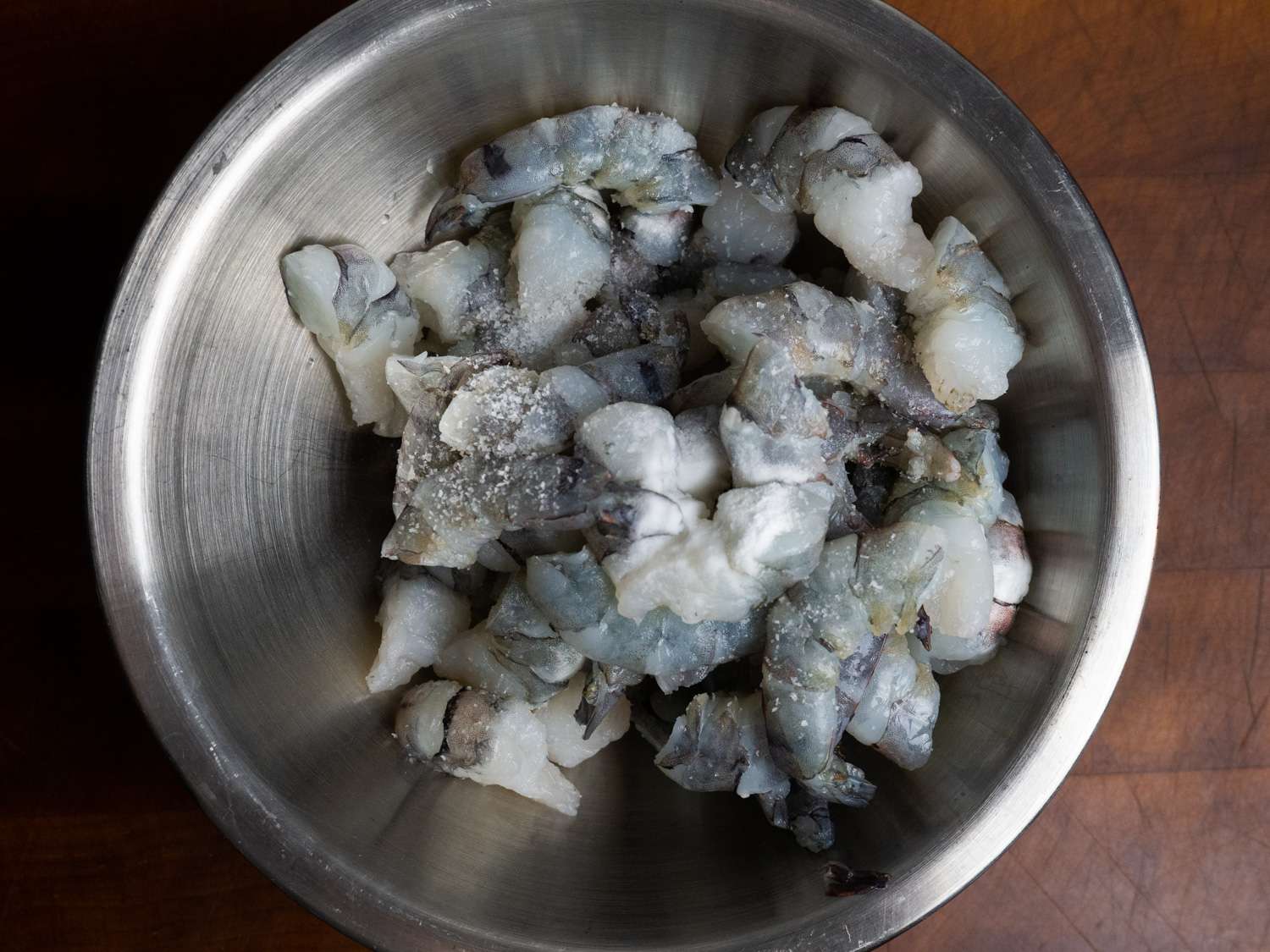 Raw shrimp in a metal bowl.