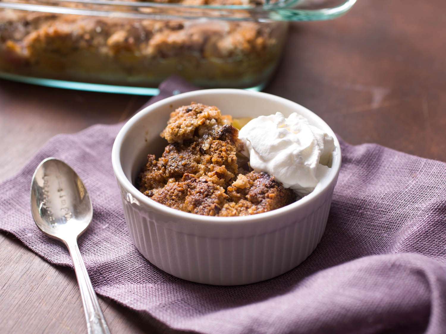 White ramekin filled with apple crisp and cream