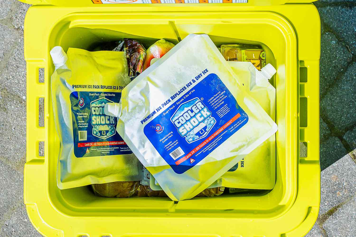 A yellow cooler containing Cooler Shock ice packs and food items