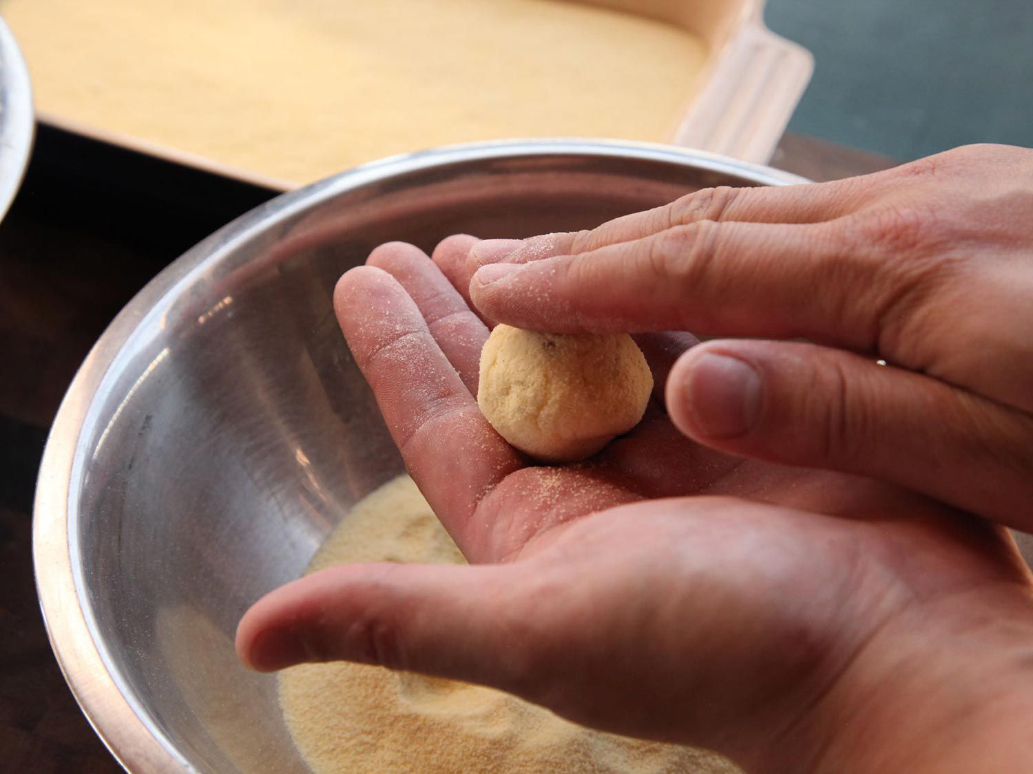 Rolling the ricotta mixture coated in semolina into small balls with fingertips. 