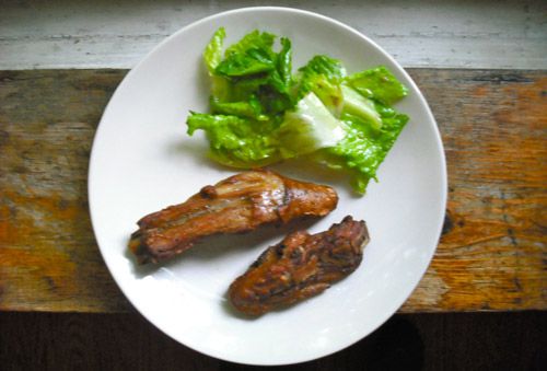 A plate with two chunks of fried pig's tail and a small salad. 