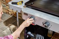 A person adjusts the temperature on the Weber 36 Inch Gas Griddle