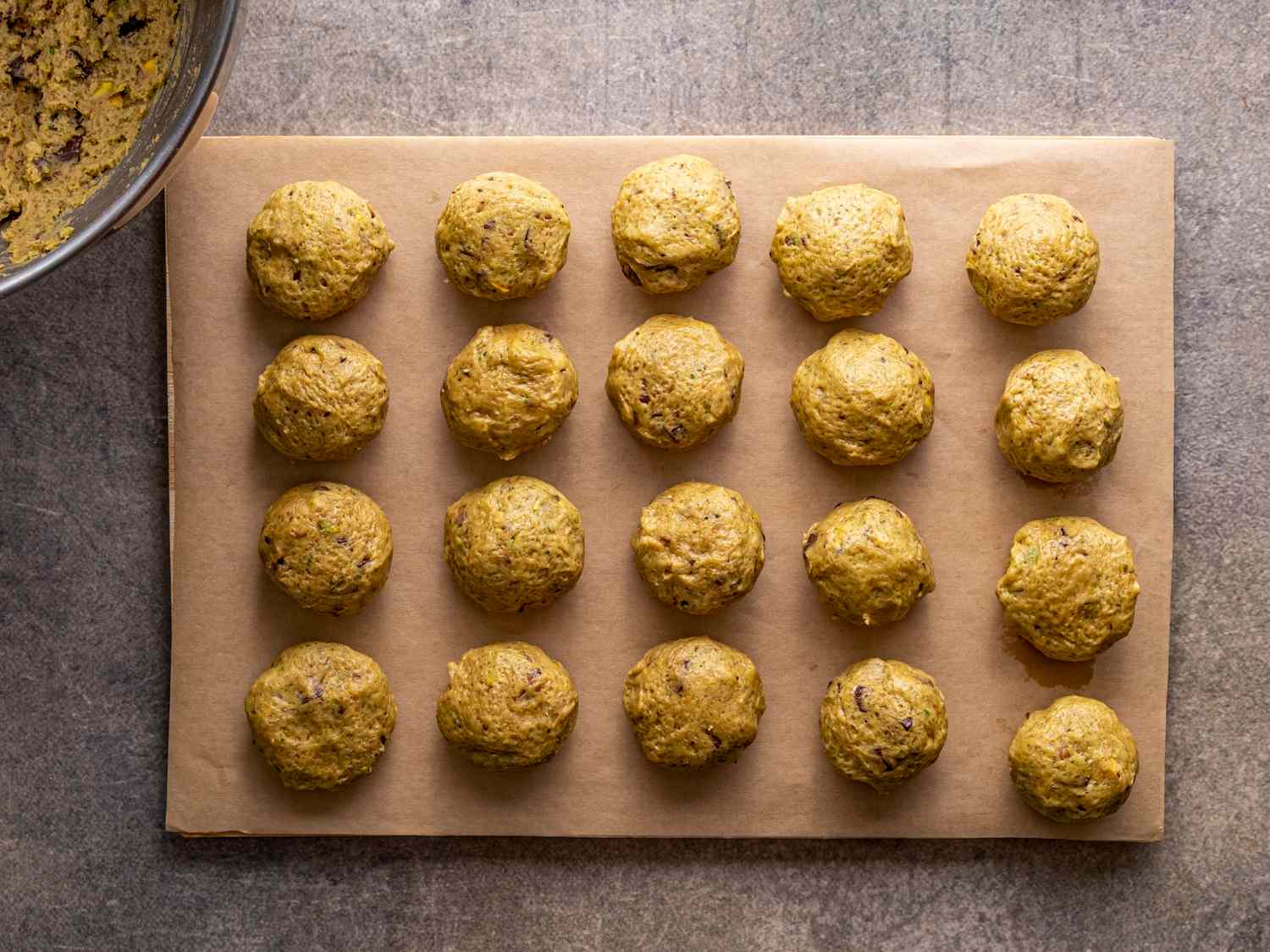 Rows of cookie dough balls on parchment paper prepared on a baking sheet