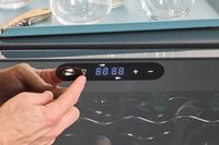 Person pressing button on Wine Enthusiast 32-Bottle Dual Zone MAX Compressor Wine Cooler